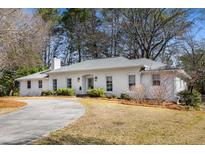 Charming white brick home with a curved driveway and lush landscaping at 4865 Northway Dr, Atlanta, GA 30342