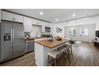 A modern, open-concept kitchen with white cabinets, stainless steel appliances, and a wood-top island at 1024 Herndon Nw St, Atlanta, GA 30318