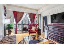 Bright living room featuring a red plush armchair, hardwood floors, and a balcony with city views at 3445 Stratford Ne Rd # 2305, Atlanta, GA 30326