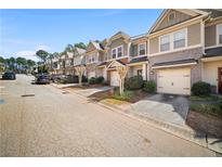 Row of two-story townhomes featuring brick and siding exteriors, individual garages, and professionally landscaped yards at 1094 N Village Dr, Decatur, GA 30032