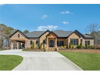 Stunning brick home features detailed trim and a circular driveway on a lush green lawn at 1244 Janmar Rd, Snellville, GA 30078