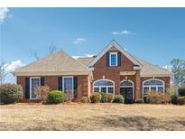 Beautiful brick home featuring a manicured lawn, complemented by lush landscaping and symmetrical design at 3999 Treemont Ln, Suwanee, GA 30024