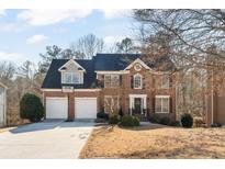 Traditional brick home featuring a two-car garage, black shutters, and a well-manicured front yard at 154 Hunters Trl, Dallas, GA 30157