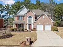 Charming two-story brick home featuring a manicured lawn and attached two-car garage at 6068 Magnolia Rdg, Stone Mountain, GA 30087