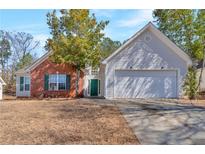 Charming brick and siding home with well-manicured lawn, attached two-car garage, and a welcoming green front door at 1025 Grace Dr, Lawrenceville, GA 30043