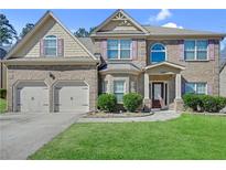 Charming two-story brick home featuring a well-manicured lawn and a convenient two-car garage at 1765 Stone Meadow Rd, Lithonia, GA 30058