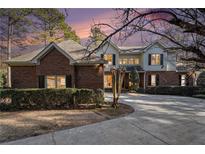 Beautiful brick and siding home with mature landscaping, a circular driveway, and a colorful sunset sky at 5930 N Eton Ct, Duluth, GA 30097