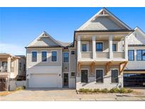 Charming two-story home with a covered porch, attached garage, brick driveway, and manicured landscaping at 320 Gray Shingle Ln, Woodstock, GA 30189