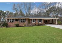 Charming brick ranch-style home featuring a well-manicured lawn, covered carport, and mature trees at 4169 Cedar Valley Ln, Conley, GA 30288