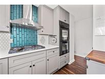 Modern kitchen with gray cabinets, stainless steel range hood, and a stylish blue tile backsplash at 6451 Katherine St, Douglasville, GA 30134