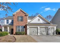 Charming two-story home featuring a brick facade, white siding, and a three-car garage at 203 Roseman Way, Woodstock, GA 30188