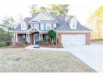 Charming two-story brick home with a well-manicured lawn, blue shutters, and an attached two-car garage at 2474 Starfire Ln, Loganville, GA 30052