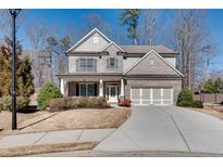 Charming two-story home with a three-car garage, manicured lawn, and inviting front porch at 5242 Park Vale Dr, Sugar Hill, GA 30518