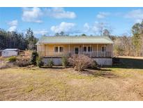 Charming exterior featuring a covered porch and a metal roof, set on a large lot with mature trees at 511 Monroe Cole Rd, Dallas, GA 30157