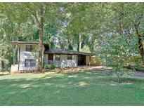 Charming two-story home with a covered carport and lush, mature trees in a large front yard at 1453 Midview Dr, Decatur, GA 30032