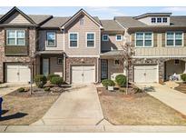 Charming townhome featuring a stone-accented facade, attached garage, and well-maintained landscaping at 5234 Mill Way, Stonecrest, GA 30083
