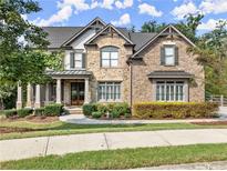 Charming two-story home with stone and brick exterior and manicured lawn at 6625 Baywood Run, Cumming, GA 30041