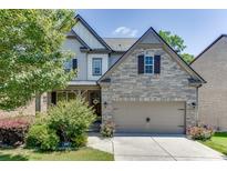 Charming two-story home featuring a stone and shingle facade, complemented by a well-manicured front yard and a two-car garage at 607 Leland Pkwy, Cumming, GA 30041