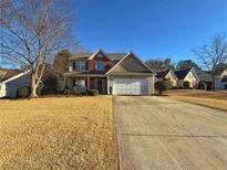 Two-story home with brick and siding exterior, well-manicured lawn, and a two-car garage with a long driveway at 2585 Kirkstone Dr, Buford, GA 30519