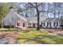 Charming white brick home featuring a brick driveway, covered porch, and beautifully landscaped front yard at 643 Longstreet Dr, Marietta, GA 30064