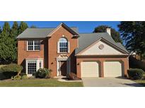 Charming two-story brick home with an attached two-car garage and manicured front lawn at 7025 Brassfield Dr, Cumming, GA 30041
