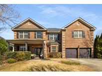 Charming two-story brick home with a well-manicured front yard, a covered porch, and an attached two-car garage at 4215 Idlewood Dr, Cumming, GA 30040