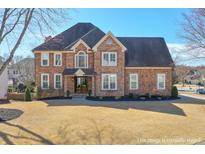 Beautiful two-story brick home with manicured lawn and mature trees at 305 Hembree Grove Trce, Roswell, GA 30076