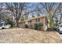 Charming single-story brick home with mature trees and minimal landscaping on a partially sunny day at 832 N Evelyn Pl, Atlanta, GA 30318