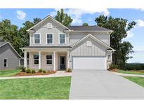Charming two-story home featuring vertical siding, a welcoming front porch, and a neatly manicured lawn at 628 Topsail Drive Pkwy, Villa Rica, GA 30180