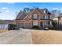 Charming brick home with a two-car garage and a well-manicured lawn, situated near a lake at 325 Morning Mist Walk, Suwanee, GA 30024