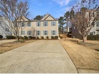 Charming townhome with beige siding and blue shutters, complemented by a spacious driveway and manicured landscaping at 4405 Thorngate Ln, Acworth, GA 30101