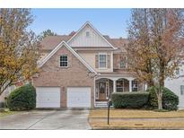 Two-story brick and siding home featuring an attached two-car garage and a covered front porch at 1312 Preserve Park Dr, Loganville, GA 30052