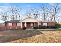 Charming brick home with a covered porch and mature trees in the front yard at 19 Roving Rd, Cartersville, GA 30121