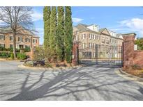 View of the gated entrance to the community with brick pillars, iron gates, and mature trees at 2102 Monhegan Se Way # 2102, Smyrna, GA 30080