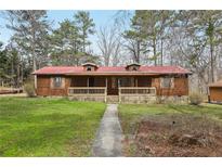 Charming single-story home featuring wood siding, a red metal roof, and a cozy front porch at 4009 Highway 138 Sw, Stockbridge, GA 30281