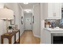 Bright hallway with hardwood floors leading to the front door and view of the kitchen counter at 4517 Twinberry Dr, Powder Springs, GA 30127