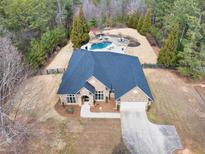Stunning aerial view of a brick home with a backyard pool and lush, wooded surroundings at 2915 Pruitt Rd, Cumming, GA 30041