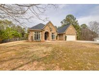 Charming brick home featuring an attached two car garage and a well manicured front lawn and garden at 2915 Pruitt Rd, Cumming, GA 30041