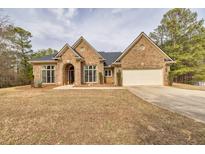 Charming brick home featuring a manicured lawn, attached garage, and traditional architectural details at 2915 Pruitt Rd, Cumming, GA 30041