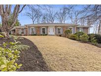 Charming brick home featuring gray shutters and manicured front yard landscaping at 4755 Huntley Dr, Atlanta, GA 30342