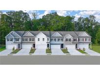 A row of new construction townhomes with individual garages and coordinated landscaping, all set against a lush green backdrop at 340 Sinclair Ct, Mcdonough, GA 30253