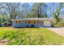 Ranch style home with a gray painted brick exterior and a well maintained front lawn at 3761 Turner Heights Dr, Decatur, GA 30032