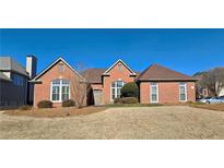 Charming brick home featuring manicured lawn, arched windows, and a classic roofline at 4875 Gladstone Pkwy, Suwanee, GA 30024