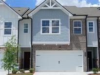 Charming townhome featuring a two-car garage, brick accents, and light blue shingle siding at 541 Tuskegee St # 49, Mcdonough, GA 30253