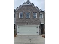 Two car garage beneath a two-story townhome with grey brick and a peak roof at 549 Tuskegee St, Mcdonough, GA 30253