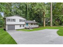 Charming home features a two-car garage and a spacious front yard with mature trees at 353 Old Rosser Rd, Stone Mountain, GA 30087