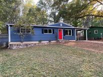 Charming blue home with a red door and a well-maintained front yard and stone retaining wall at 1504 Sycamore Nw Dr, Kennesaw, GA 30152