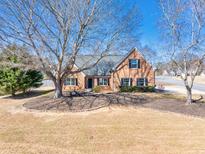 Charming one-story brick home with a well-manicured front yard, complemented by mature trees and black shutters at 1270 Platinum Dr, Hoschton, GA 30548