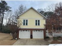 Charming two-story home featuring a two-car garage and a yellow exterior at 3423 Conley Downs Drive, Powder Springs, GA 30127