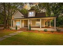 Charming home featuring a spacious covered porch, green lawn, mature trees, and a stone pathway at 159 Forest Ave, Social Circle, GA 30025